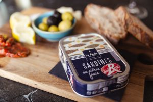 Nahaufnahme einer Sardinendose (blau) mit Beilagen.