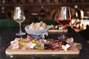 Vesperplatte mit Wurst, Käse und zwei Weingläsern.