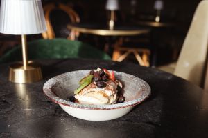 Tiramisu mit frischen Früchten unter einer Tischlampe.