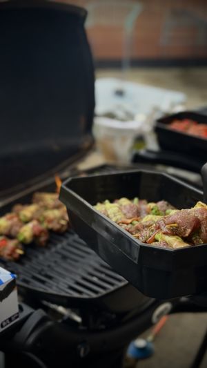 Rohe Grillspieße in einer Schale und ein Grill