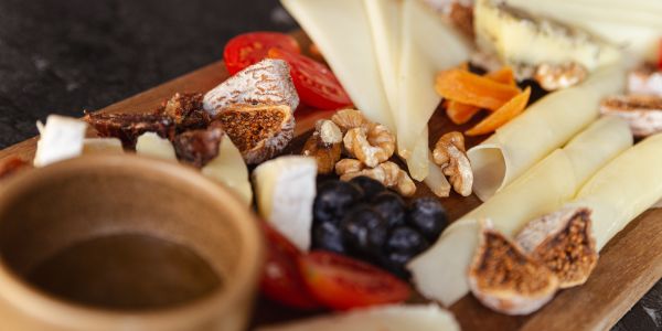 Käseauswahl mit Feigen, Tomaten, Trauben und Nüssen.